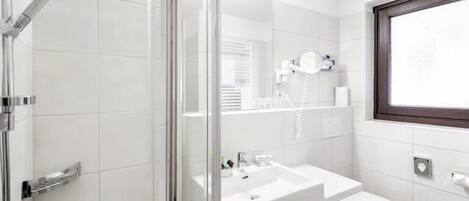 A modern bathroom with a glass shower enclosure, a white sink, and a toilet.
