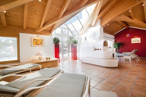 Una habitación amplia con vigas de madera, un ventanal grande y una pared roja decorativa.