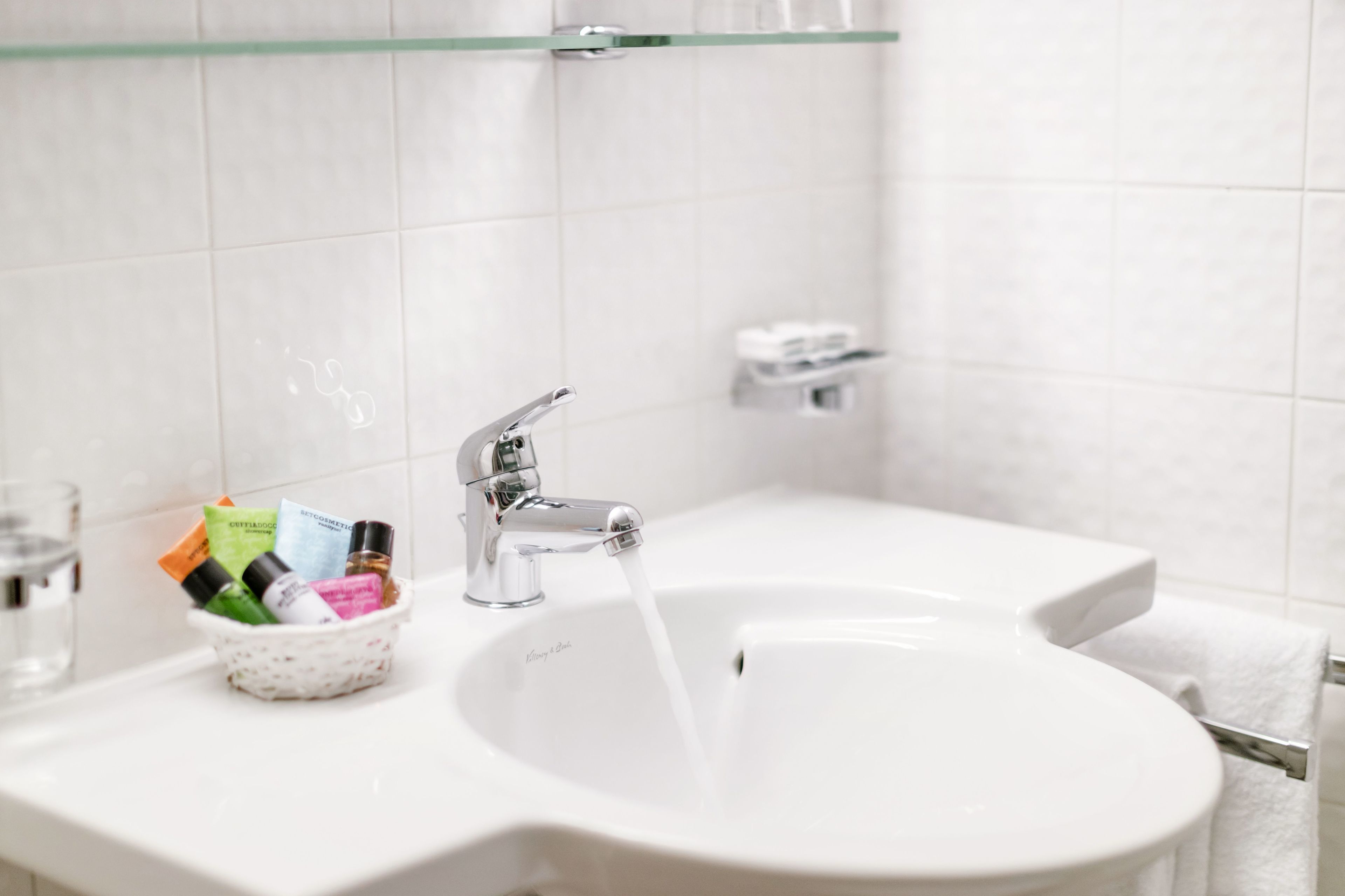 A bathroom sink with a glass bowl containing toiletries, a faucet, and a towel rack.
