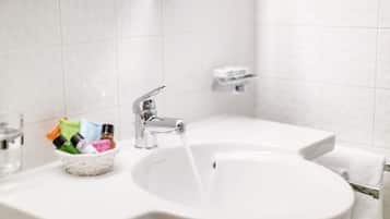A bathroom sink with a glass bowl containing toiletries, a faucet, and a towel rack.