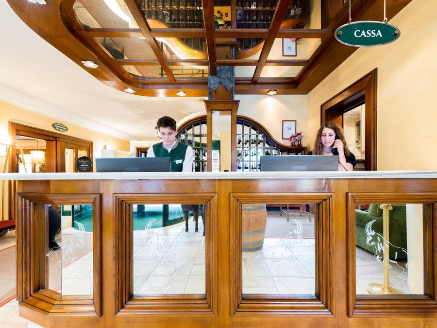 Una zona de recepción con mostrador de madera, un letrero que dice "CASSA" y vistas del vestíbulo a través de paneles de vidrio.