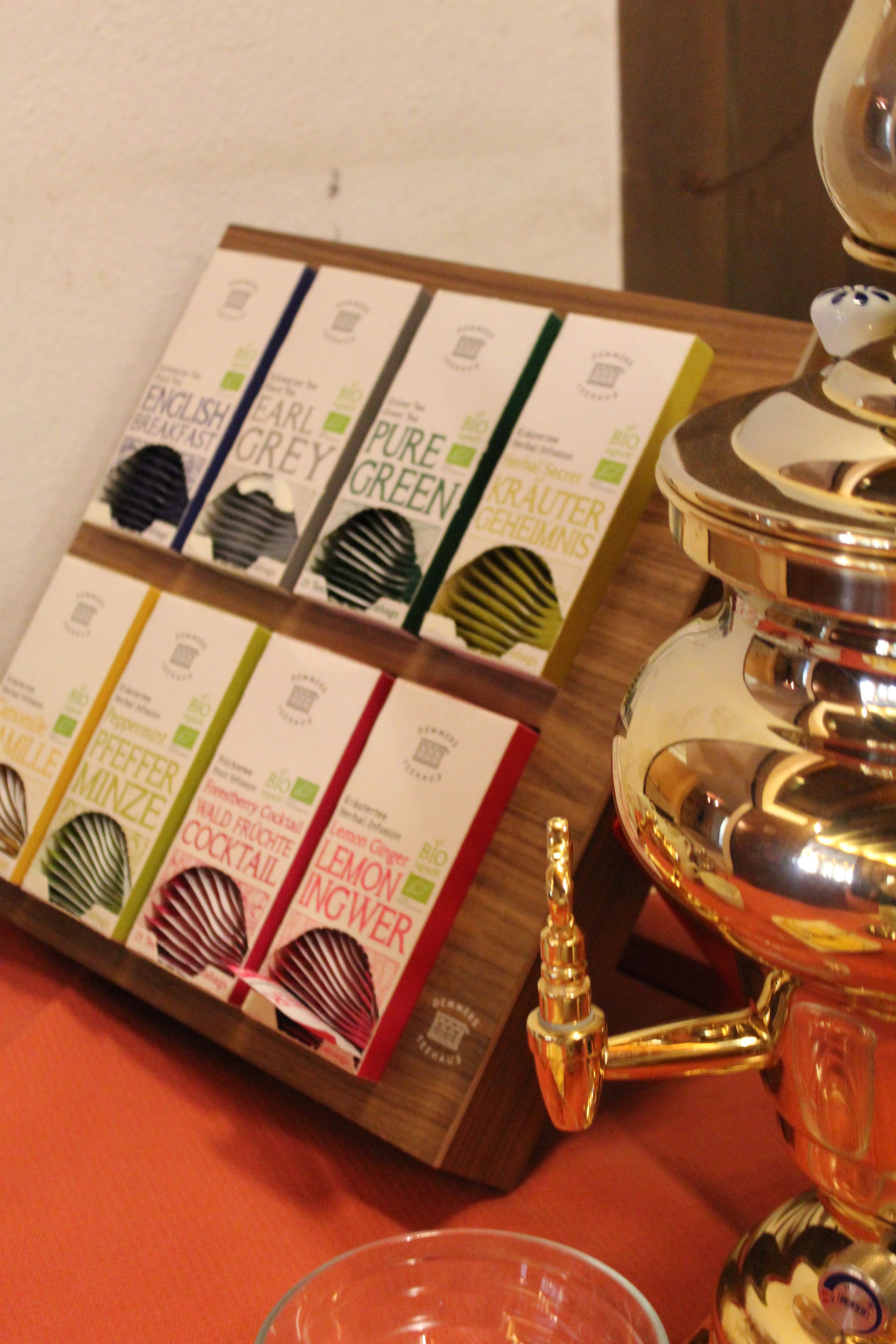 Un plateau contenant divers produits emballés et une théière de couleur dorée, posé sur une table.