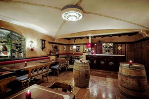Un restaurante acogedor con mesas y bancos de madera, una zona de bar y barriles de madera.