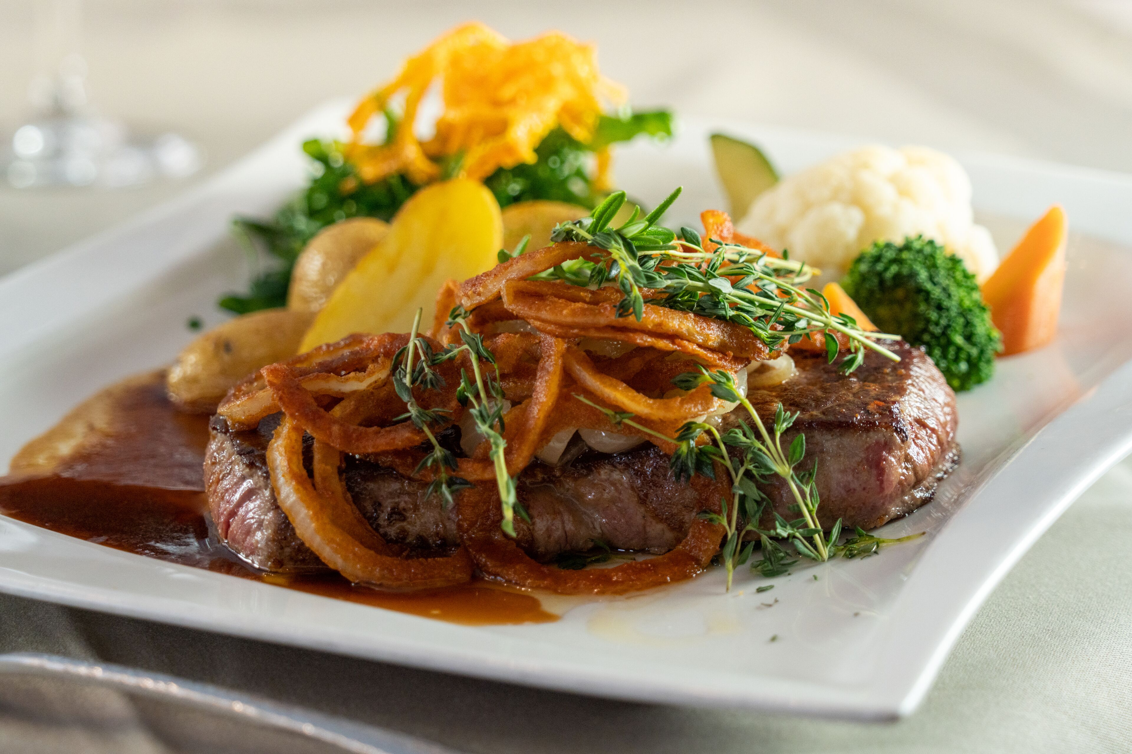 A plated meal with steak, vegetables, and a sauce.