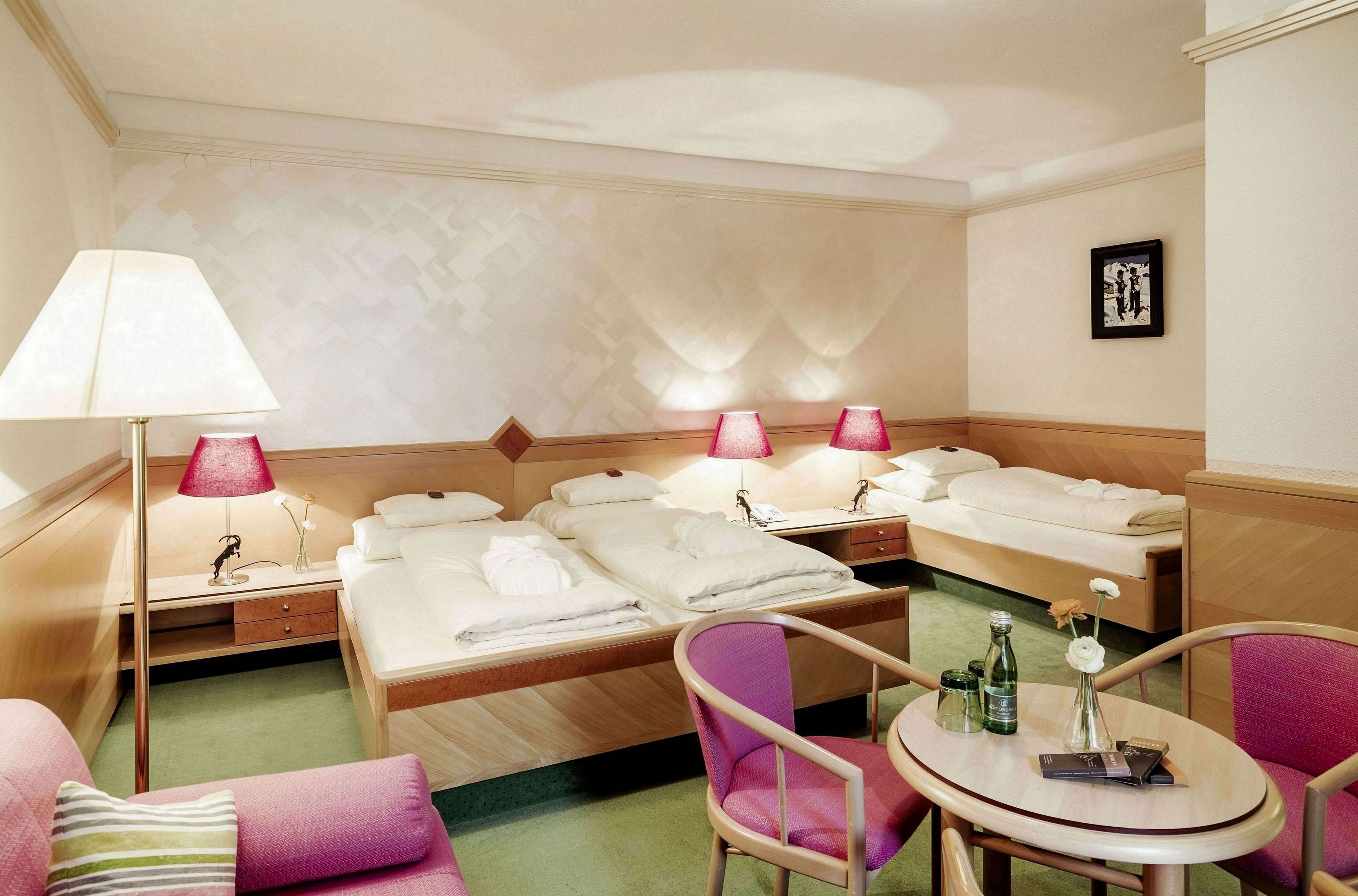 Ein Hotelzimmer mit zwei Betten, einem Schreibtisch, einem Stuhl und einem Tisch mit einer Vase und Büchern.