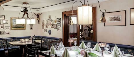 Un comedor con una zona de asientos tipo banca, una mesa redonda con mantel blanco y una araña.