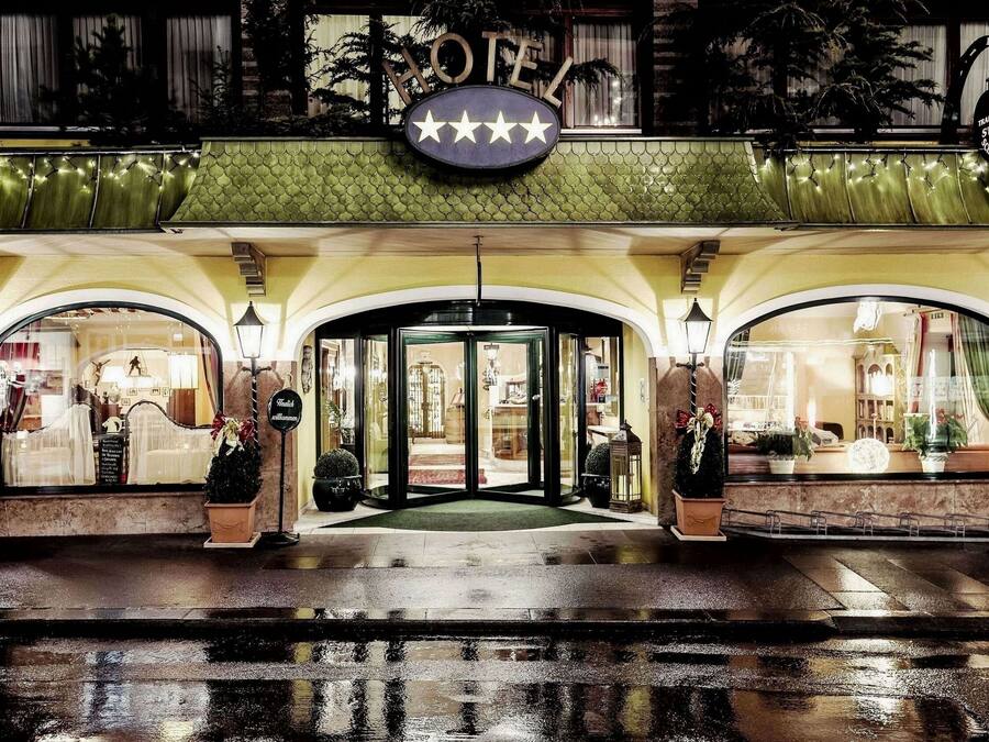 Entrada de hotel con un letrero que indica cinco estrellas, un toldo verde y una puerta de cristal.