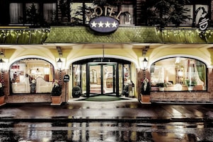 Entrada de hotel con un letrero que indica cinco estrellas, un toldo verde y una puerta de cristal.