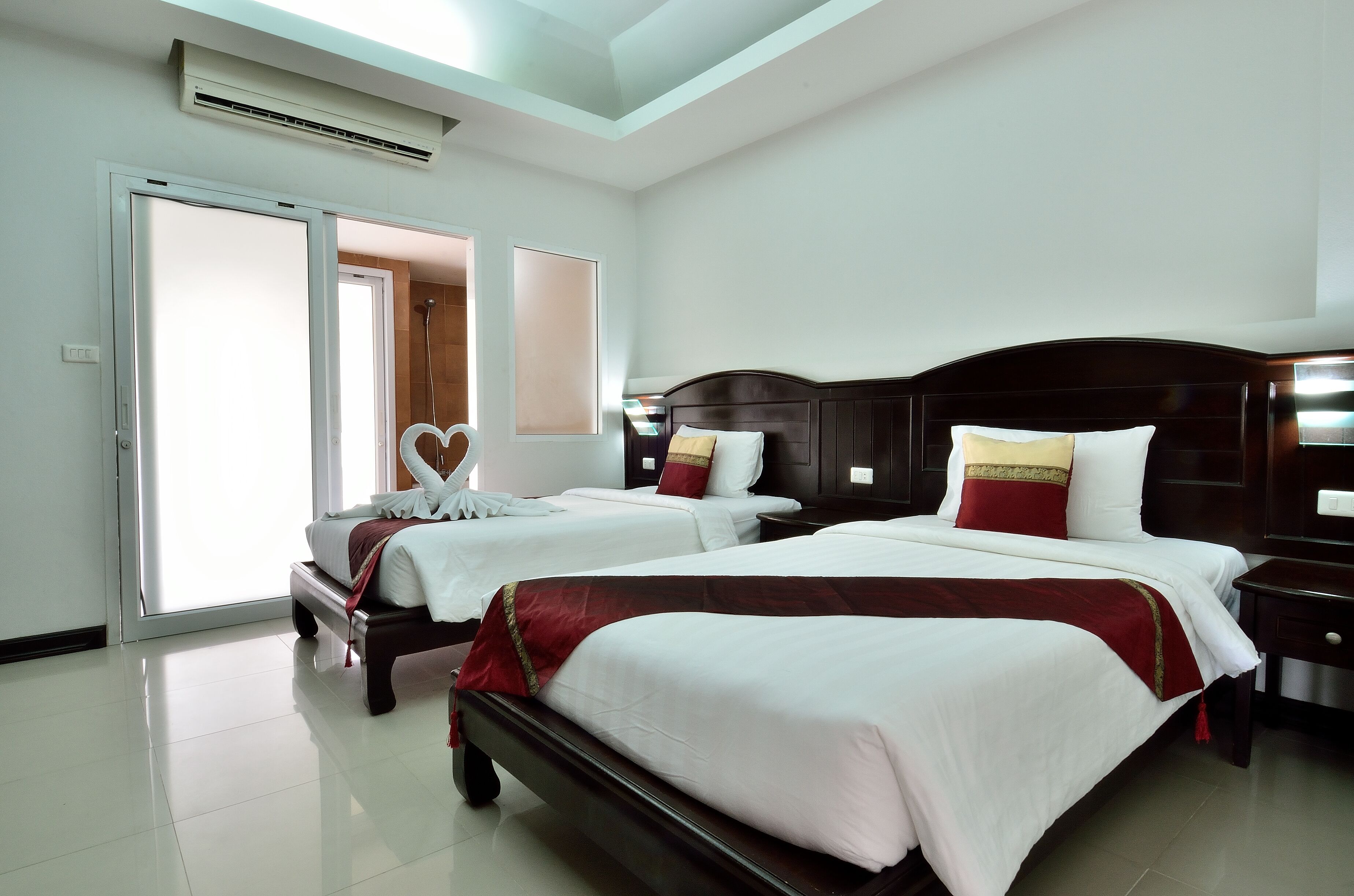 A hotel room with two beds, a large window, and a sliding door leading to a balcony.