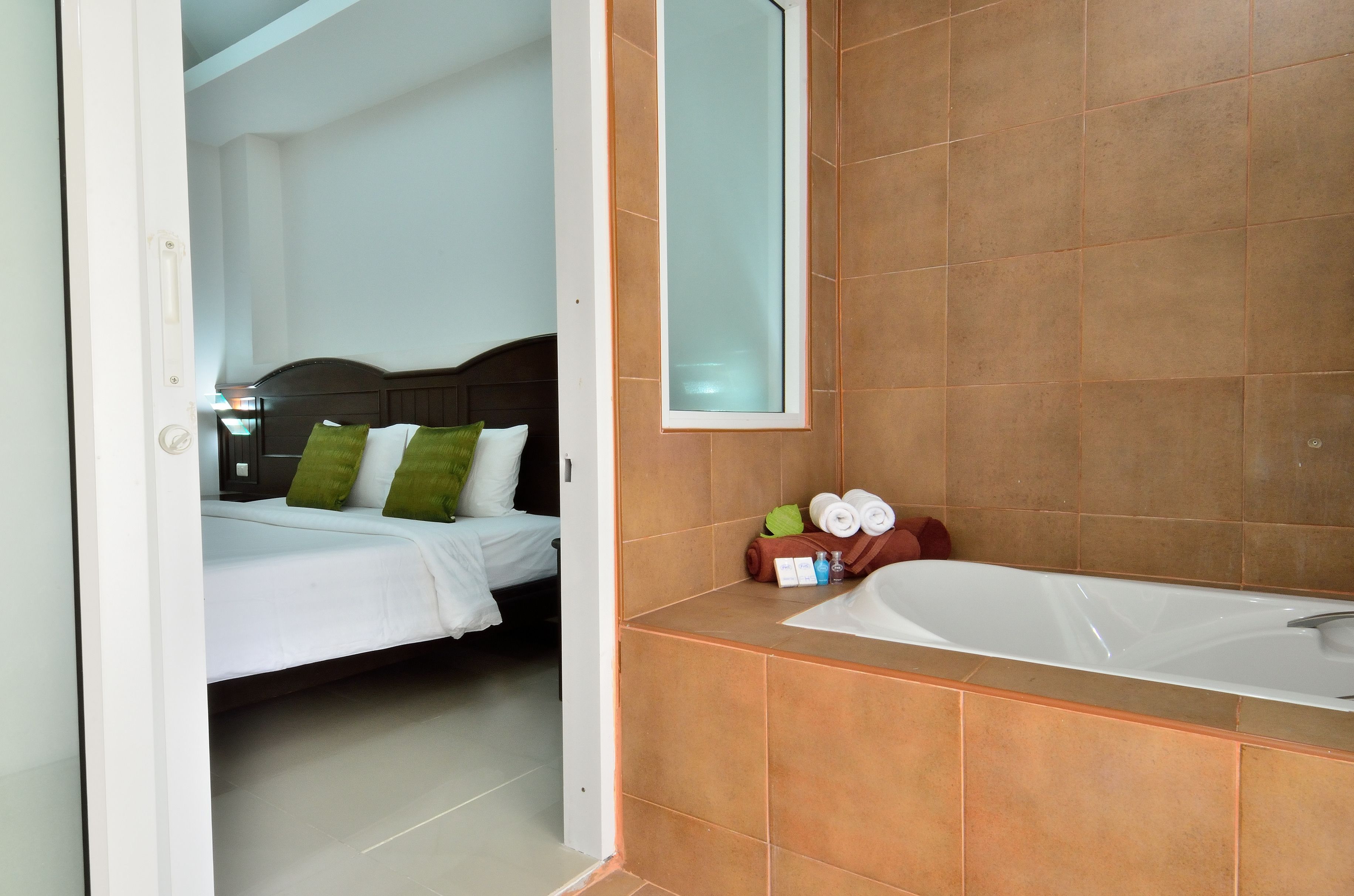 Quarto de hotel com cama, banheiro com banheira e espelho.