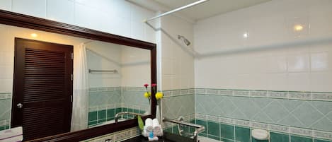 A bathroom with a white sink, a mirror, a bathtub, and green-tiled walls.