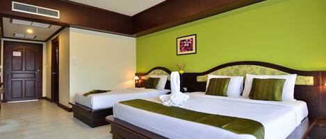 A hotel room with two beds, a green wall, and a wooden headboard.