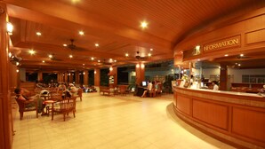 Un hall d’entrée spacieux, doté d’un plancher en bois et d’un comptoir de réception portant l’inscription « RENSEIGNEMENTS ».