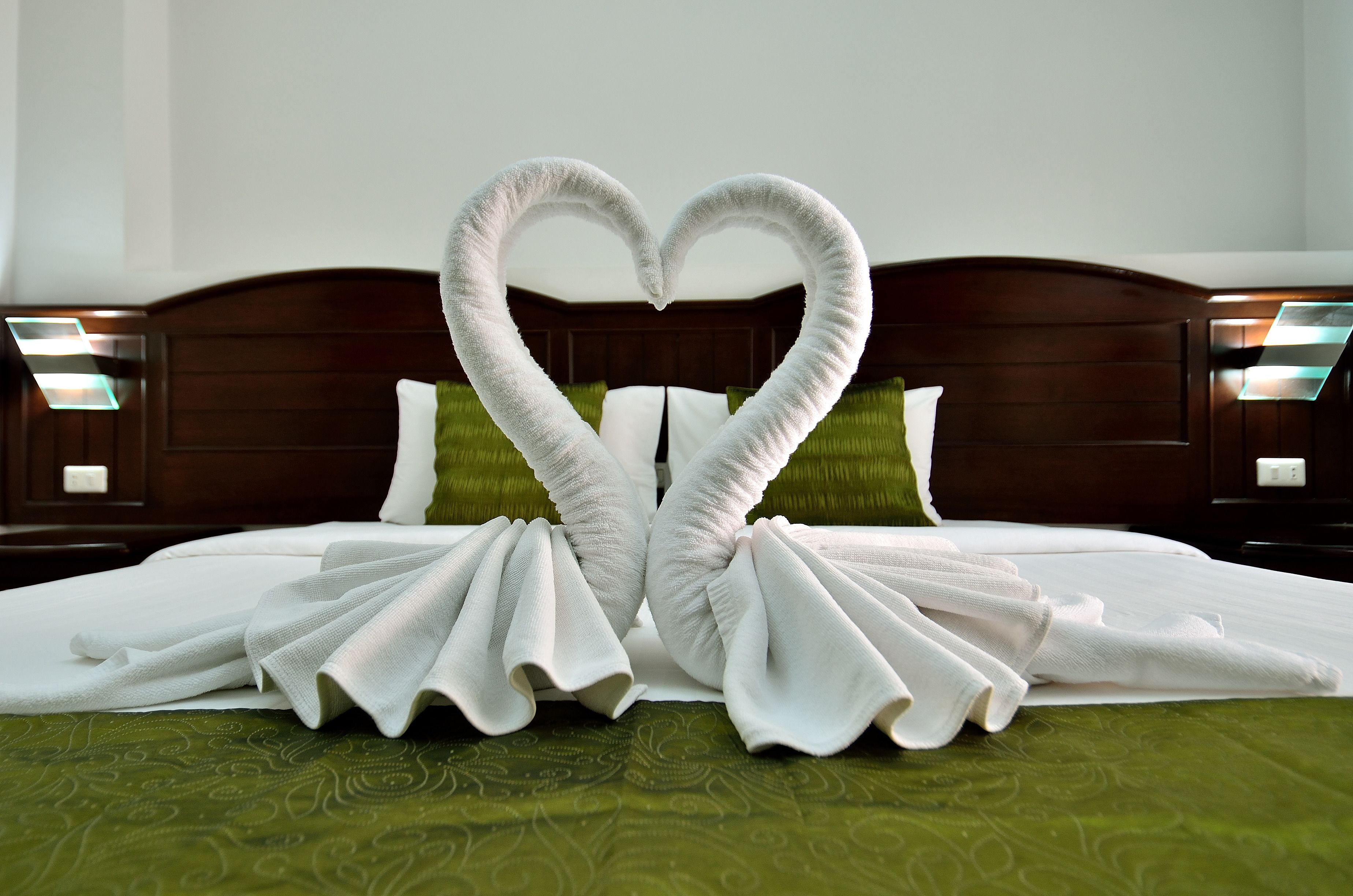Una cama con una colcha verde y dos almohadas blancas.