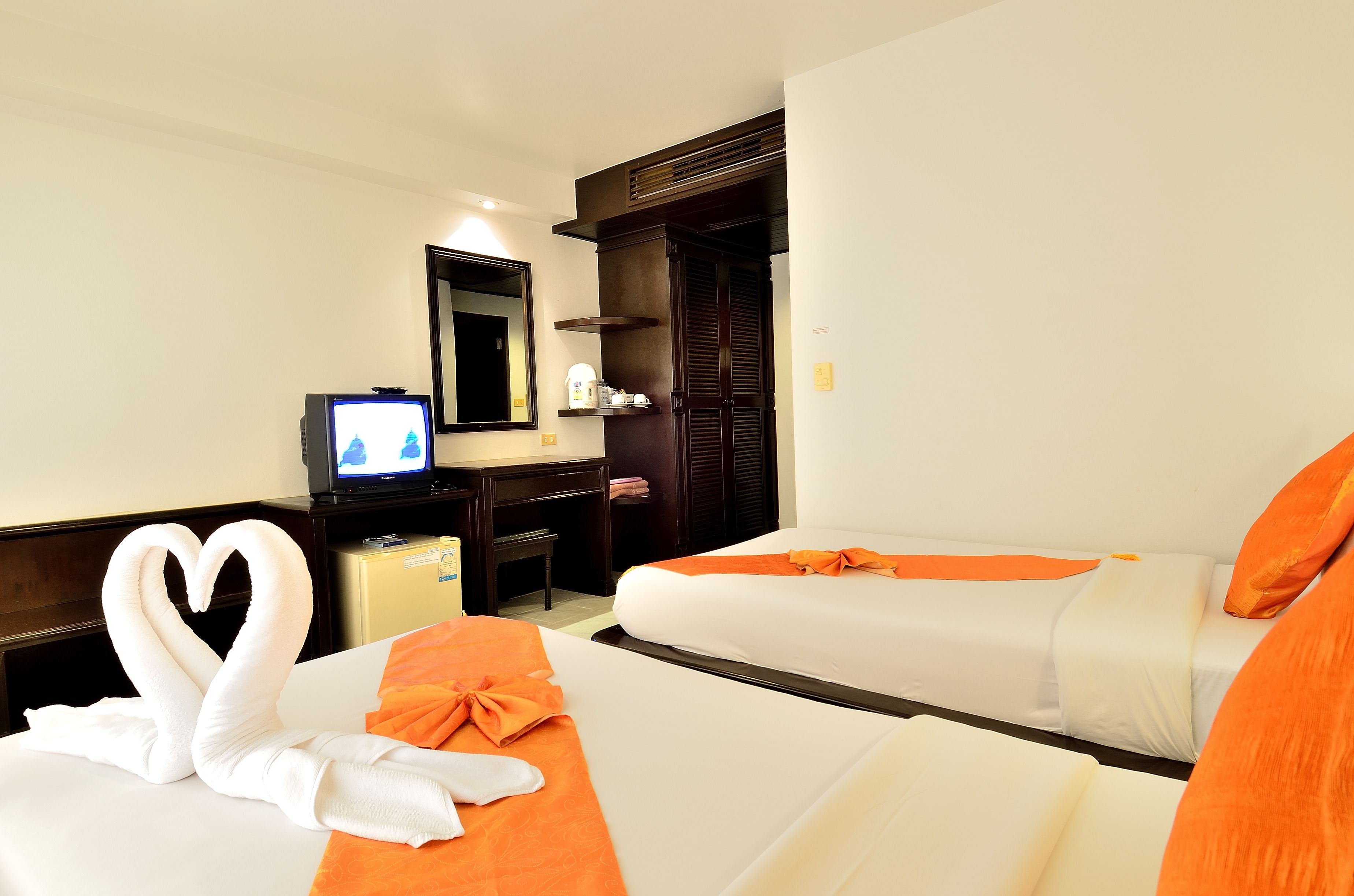 A hotel room with two beds, a TV, a desk, and a wardrobe.