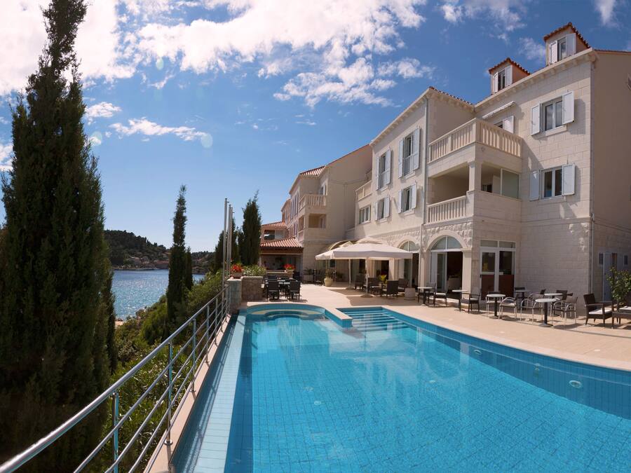 Una piscina al aire libre, sombrillas, sillones reclinables de piscina