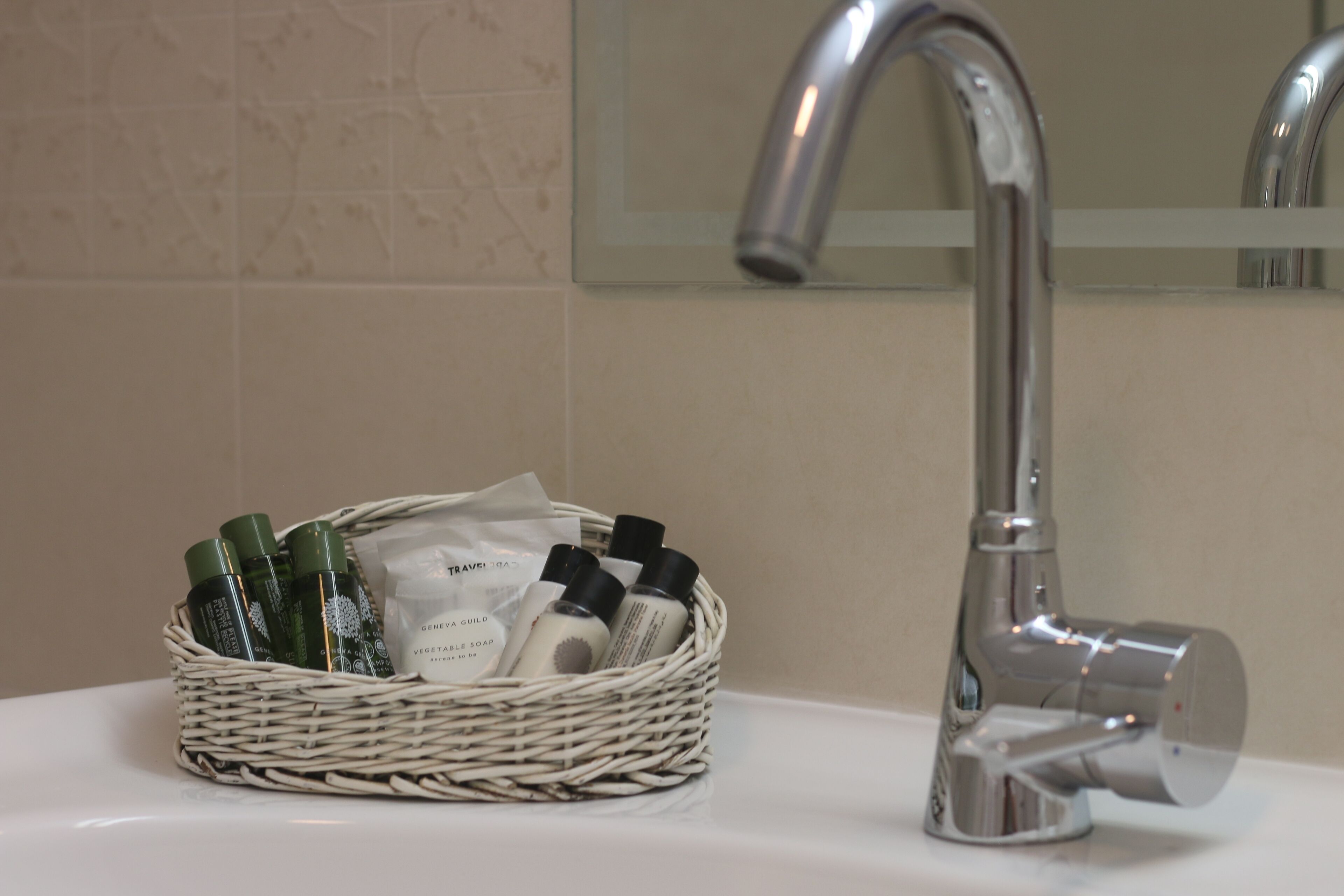 Un lavabo de salle de bain avec un robinet chromé et un panier en osier contenant des articles de toilette.