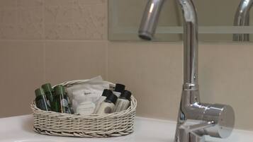 Un lavabo de salle de bain avec un robinet chromé et un panier en osier contenant des articles de toilette.