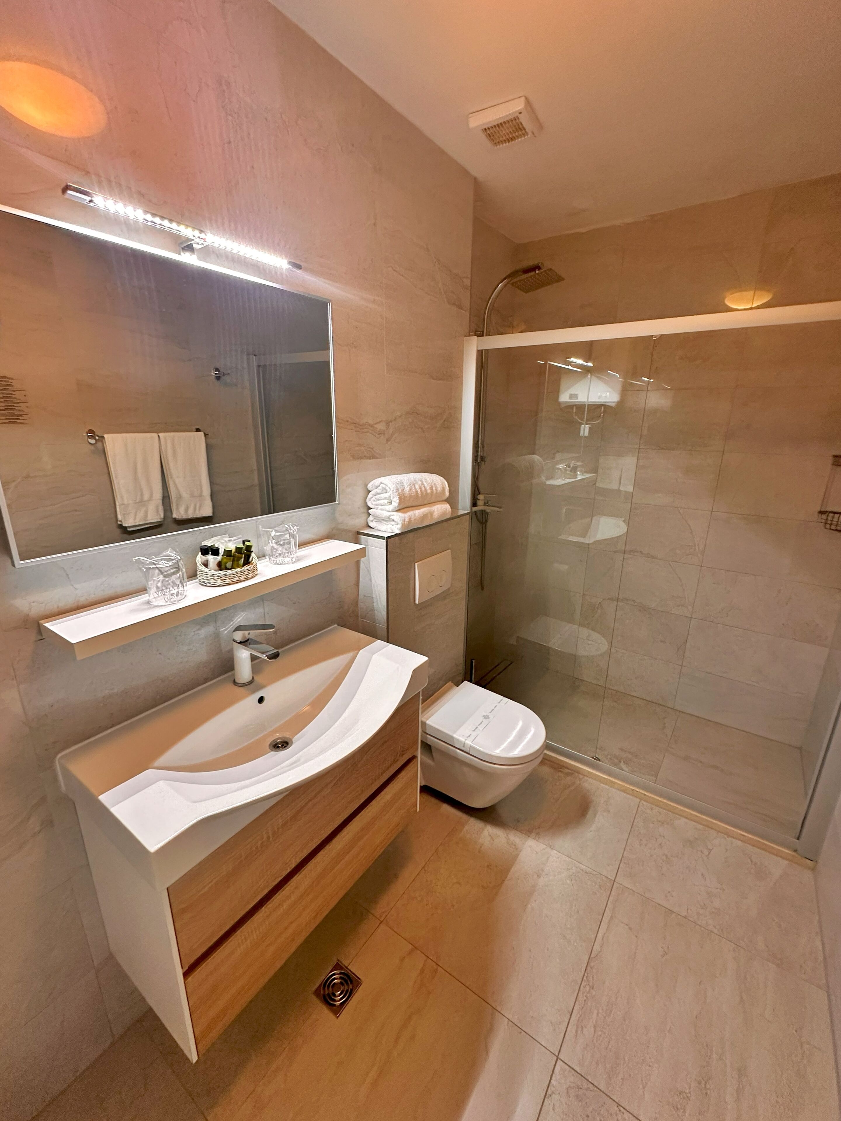 A modern bathroom with a curved sink, a glass shower enclosure, and a large mirror.