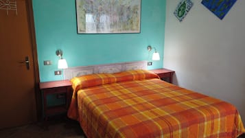 Una habitación con una cama, dos mesitas de noche, una lámpara de pared y una puerta.