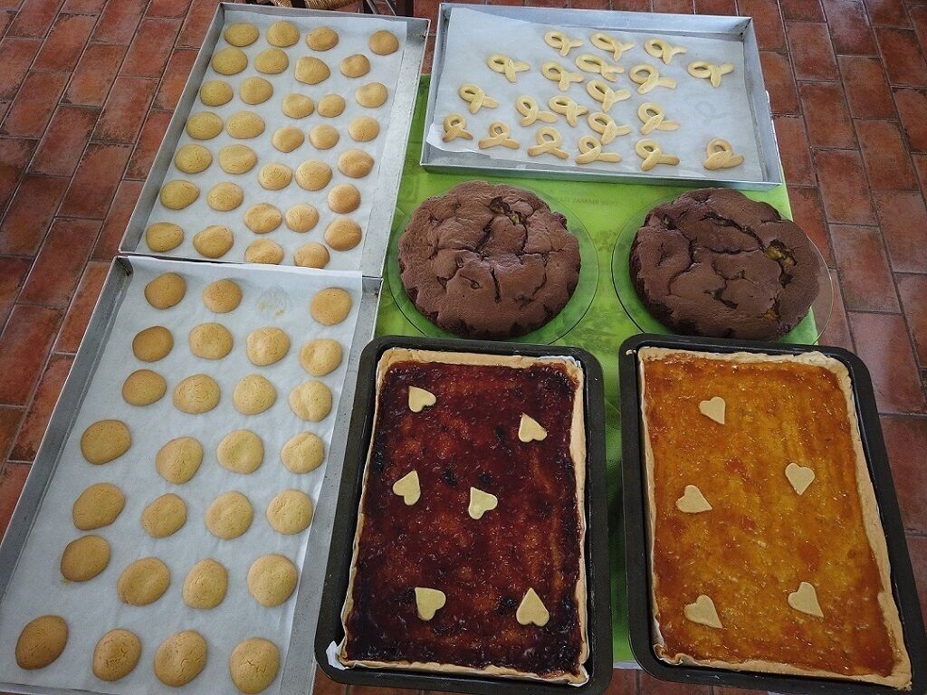 Trays of baked goods including cookies, brownies, and a tart with heart-shaped decorations.