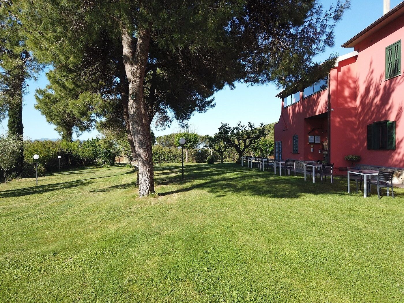 Un edificio rojo con terraza al aire libre y un árbol grande al frente.