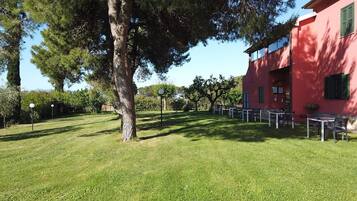 Un edificio rojo con terraza al aire libre y un árbol grande al frente.