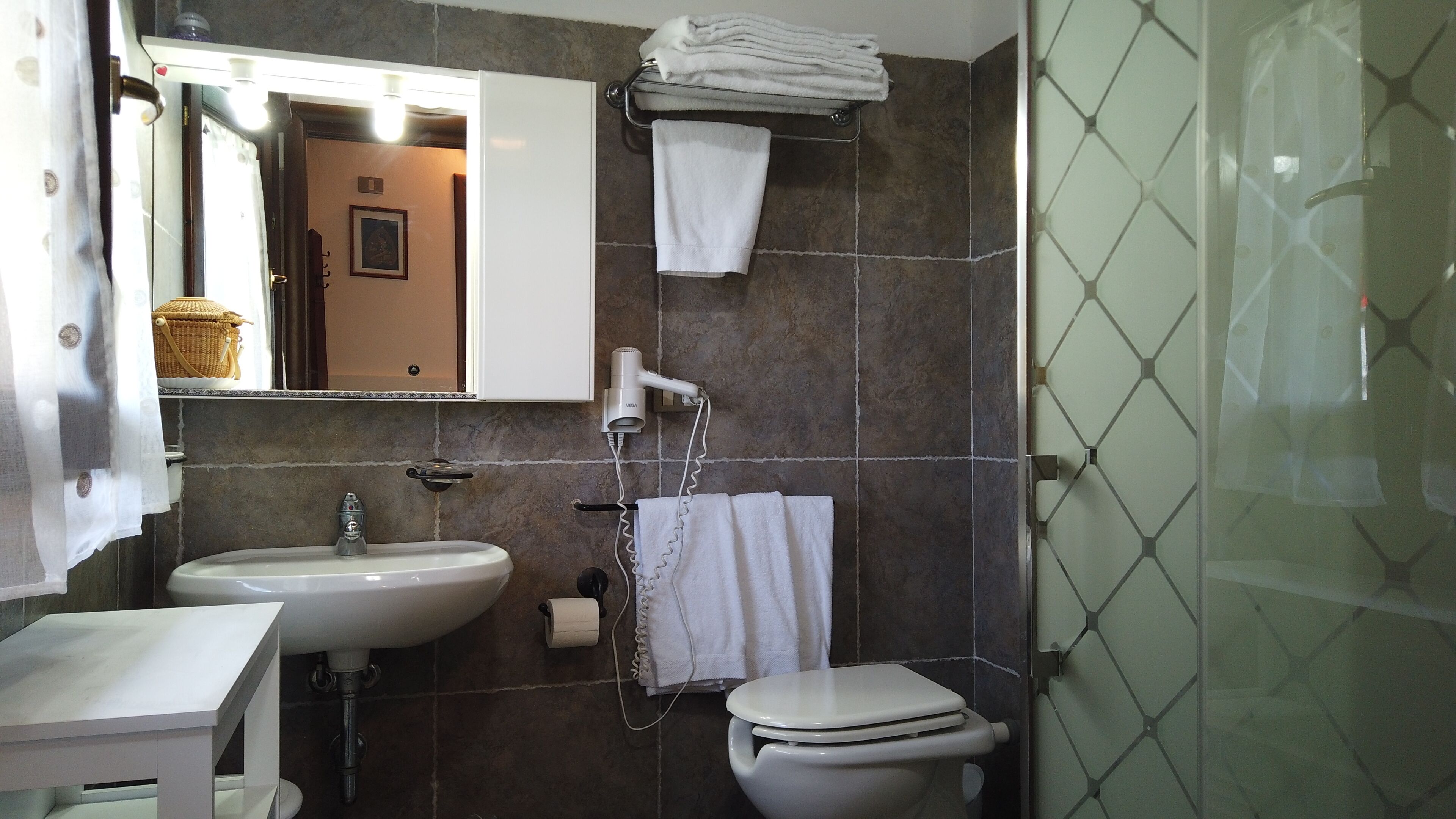 A bathroom with a sink, toilet, and a hairdryer mounted on the wall.