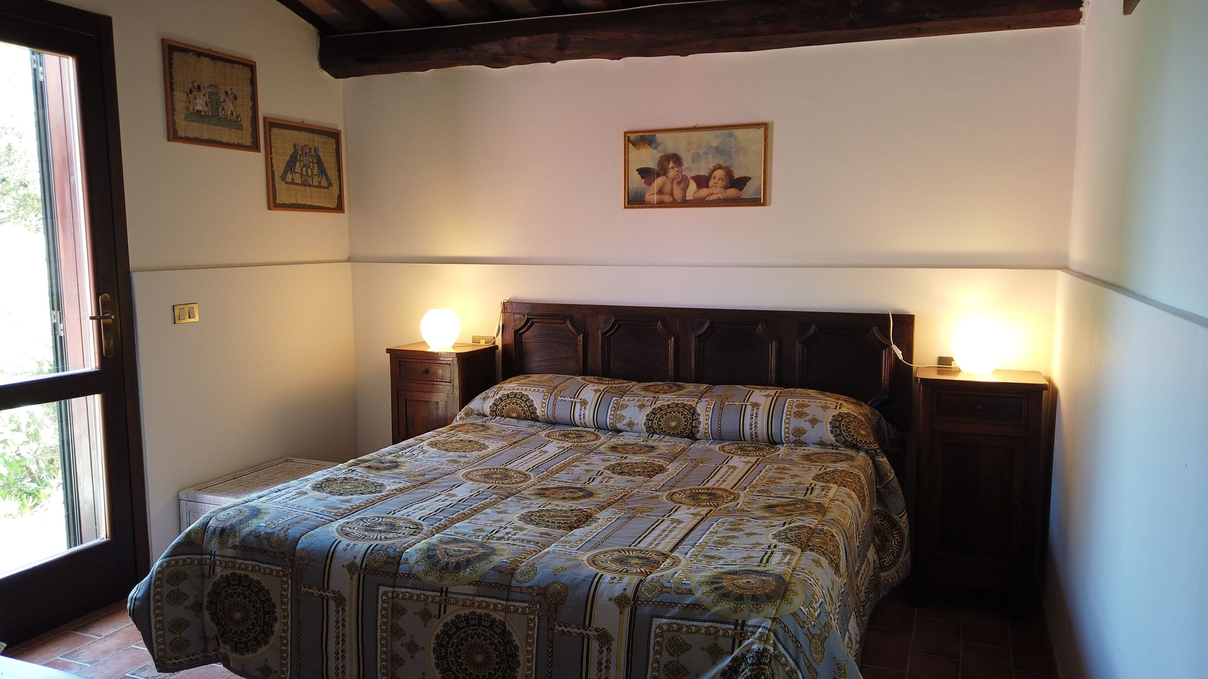 Una camera da letto con un letto grande, due comodini con lampade e tre quadri appesi al muro.
