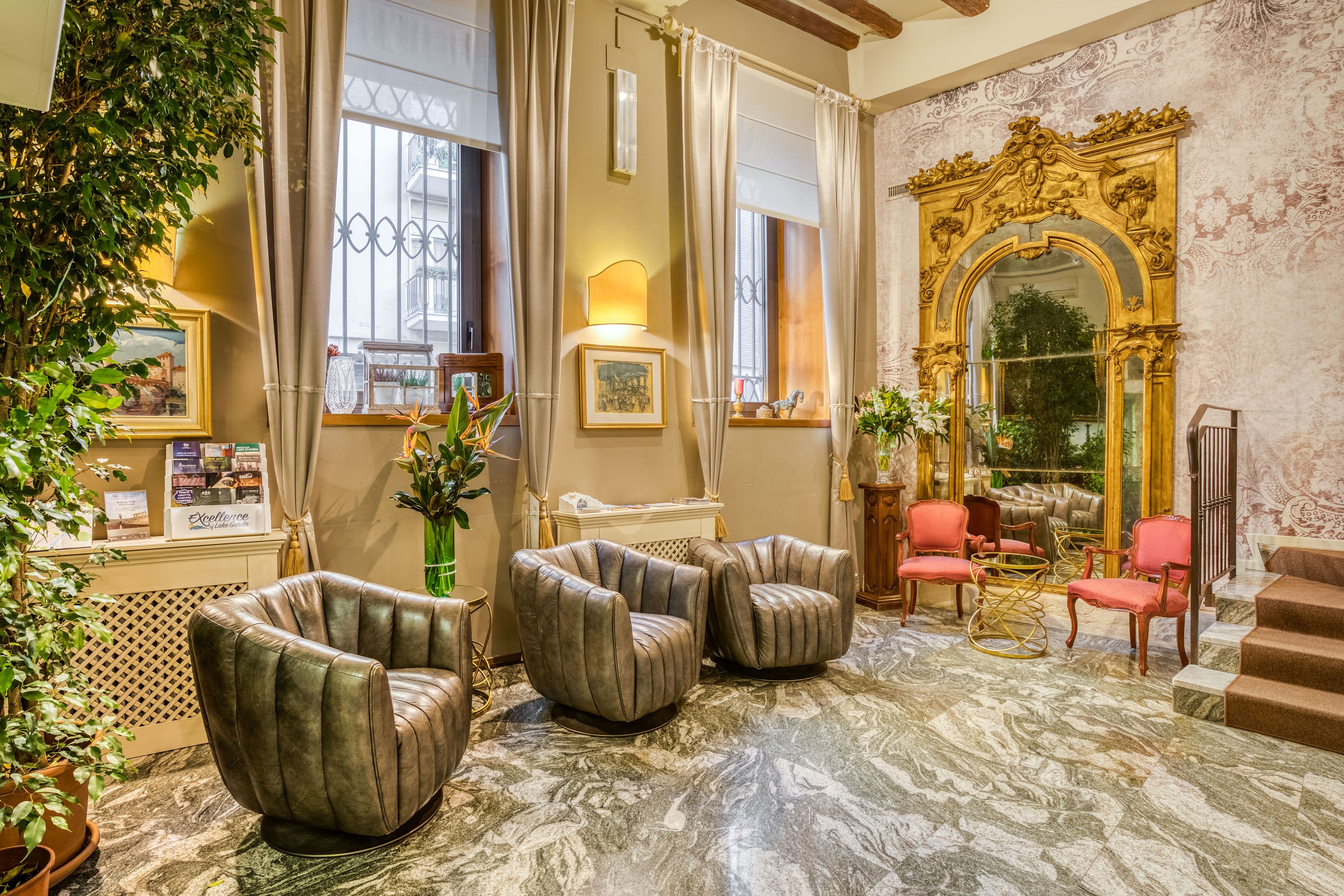 A luxurious lobby with leather armchairs, a grand mirror, and a marble floor.