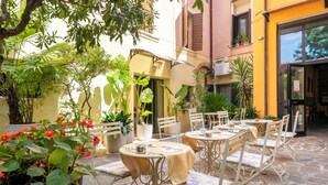 An outdoor café with metal chairs and tables, surrounded by potted plants and a stone floor. - Boutique Hotel Scalzi - Adults Only (Verona)