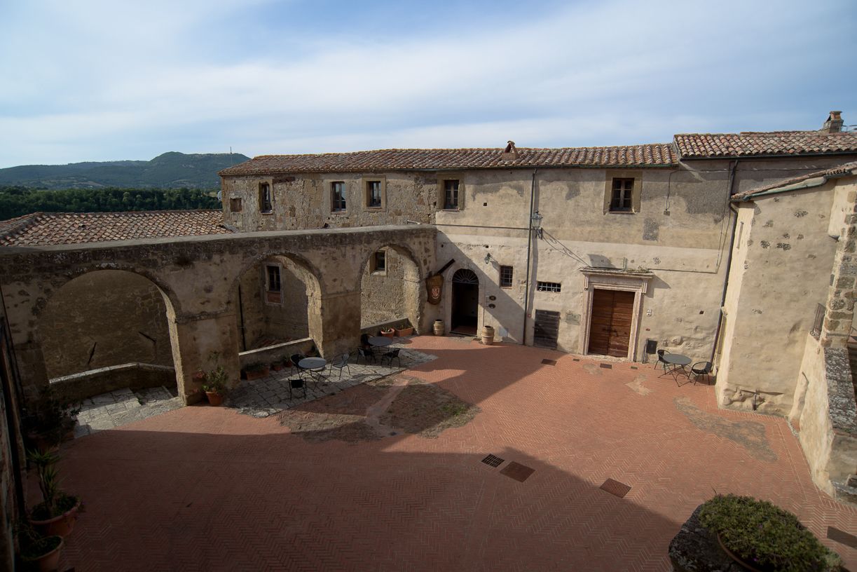 Un patio con suelo de baldosas, paredes de piedra y arcos.