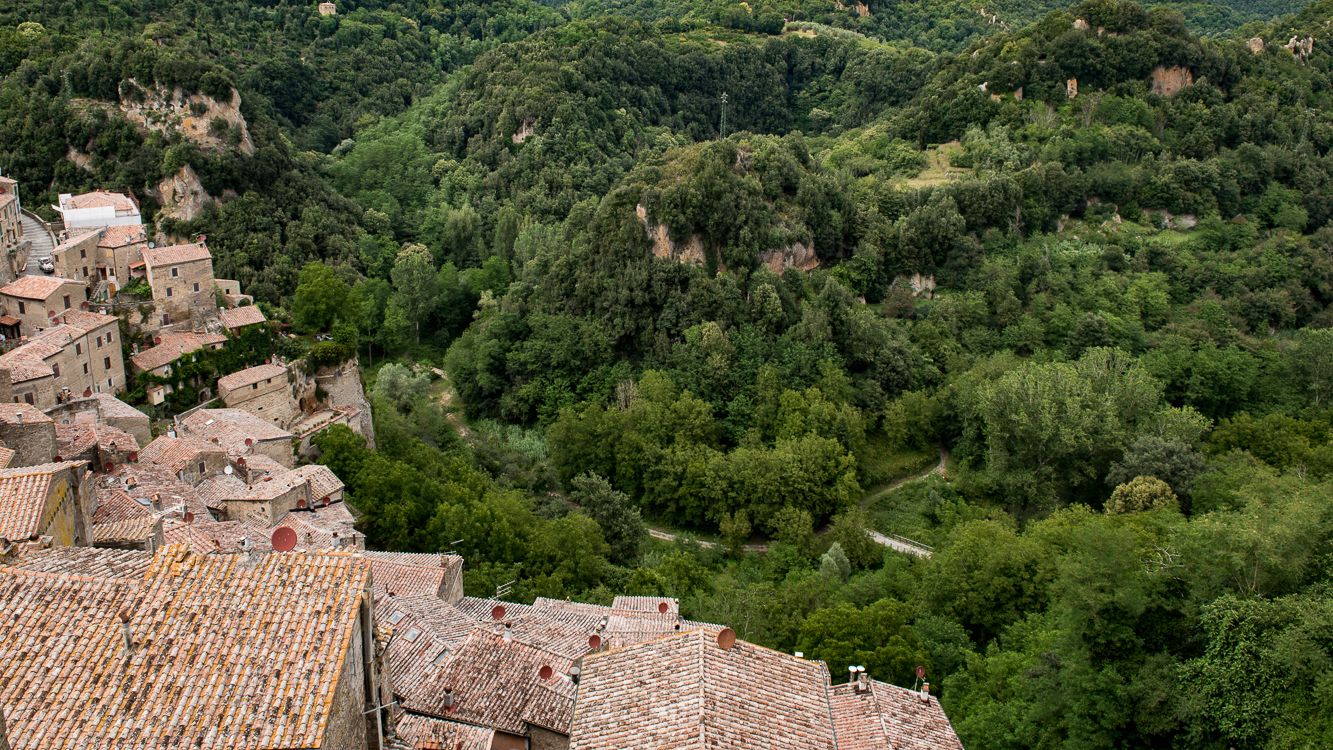 Un village aux bâtiments aux toits de tuiles rouges, niché dans une vallée verdoyante.