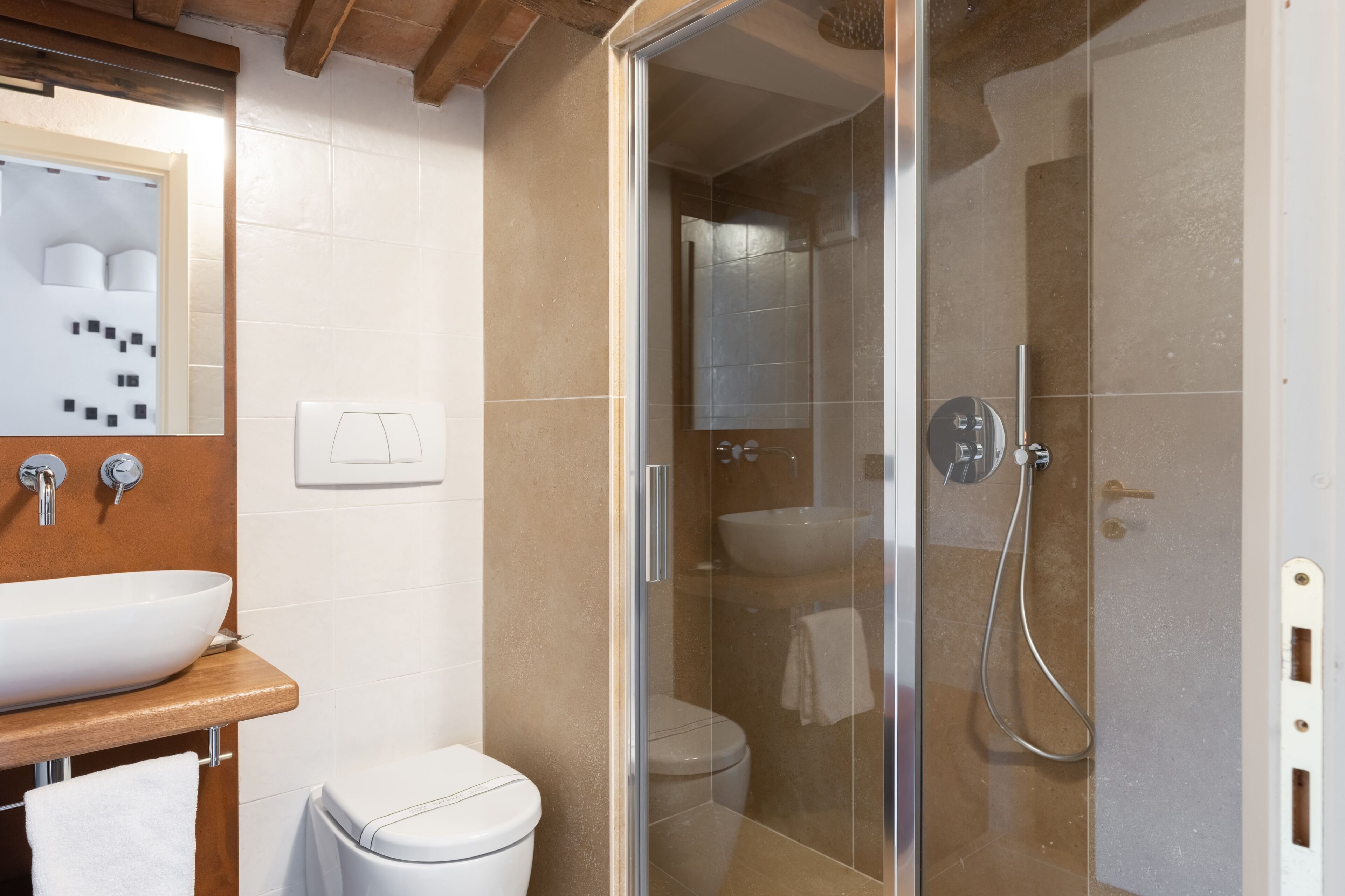 A bathroom with a glass-enclosed shower, a white sink, and a toilet.