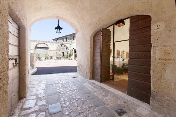 An arched stone corridor with a cobblestone floor, leading to a courtyard with a building in the background. - Hotel della Fortezza (Sorano)