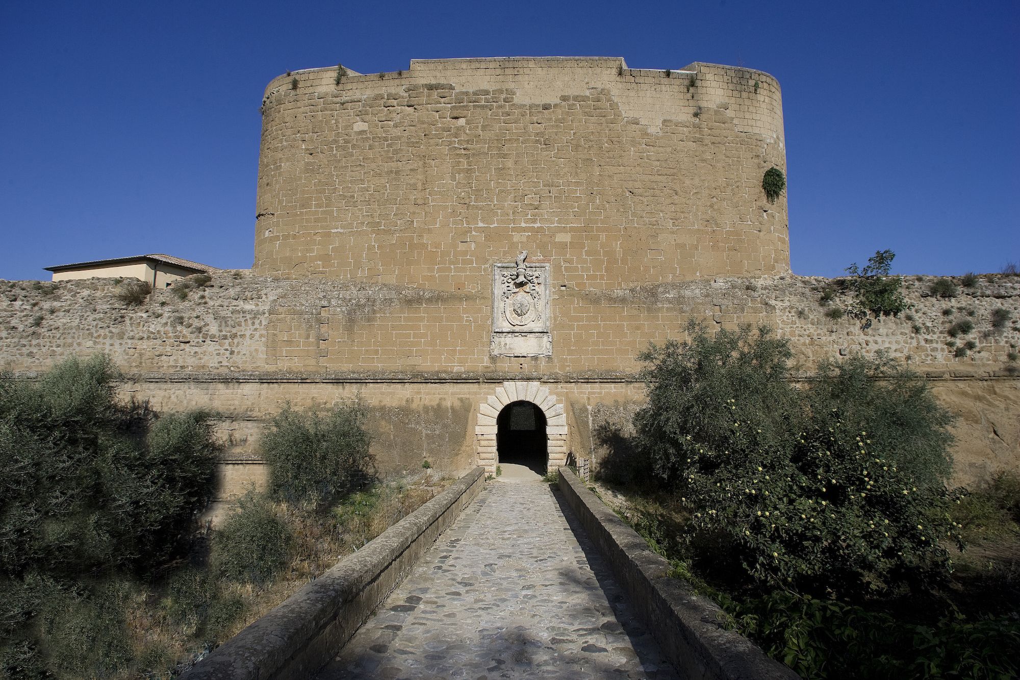 A stone fortress with a central arched entrance and a crest above it.