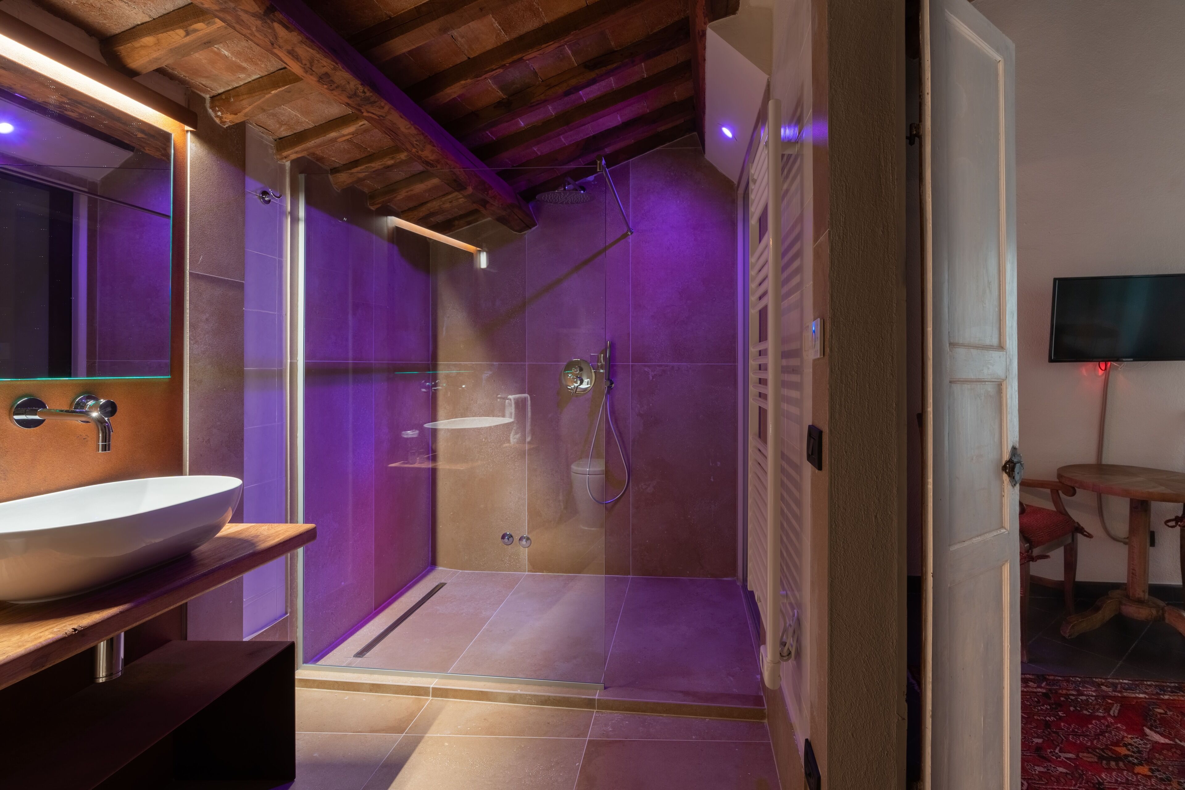 Une salle de bain moderne avec une douche à parois de verre, un meuble-lavabo en bois et un grand miroir.