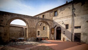 An outdoor courtyard with a brick floor, stone arches, and a building with a tiled roof. - Hotel della Fortezza (Sorano)