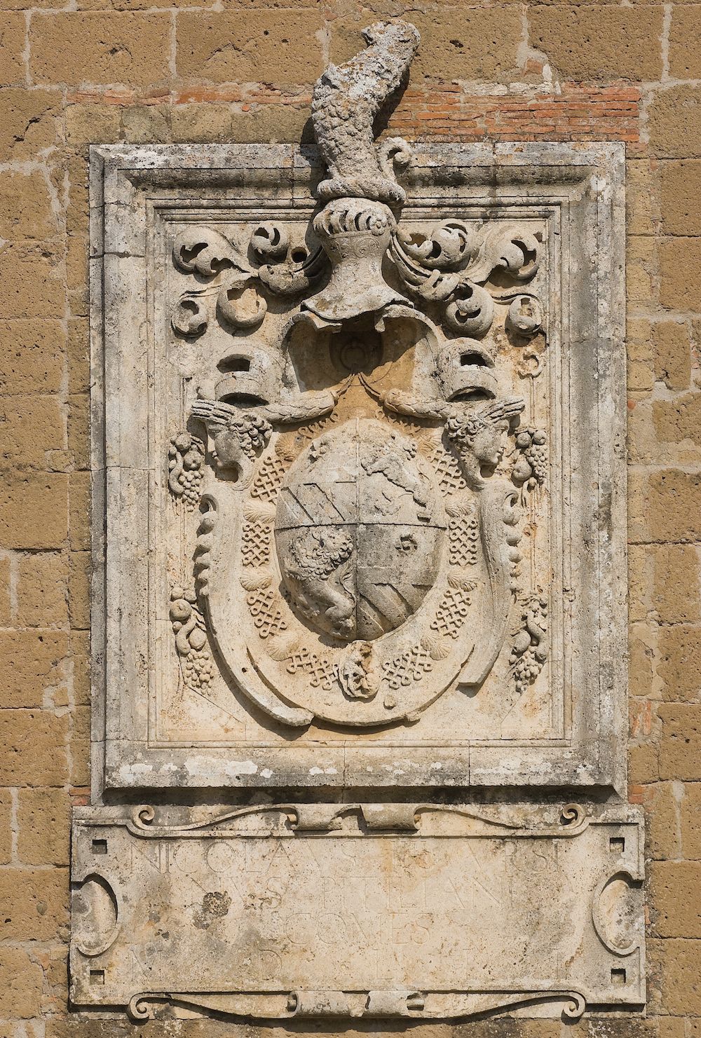Un relieve de piedra con un escudo, posiblemente un escudo de armas, en una pared de ladrillo.