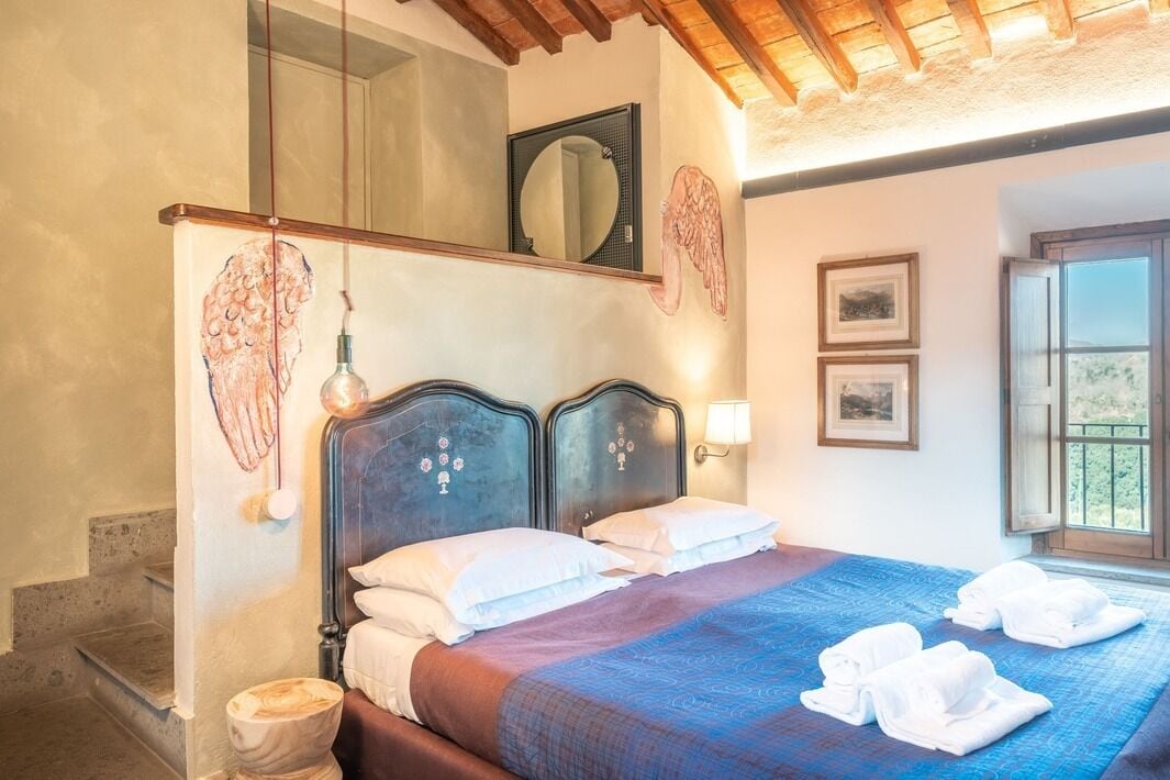A bedroom with a bed, a mirror, a window, and a towel rack.