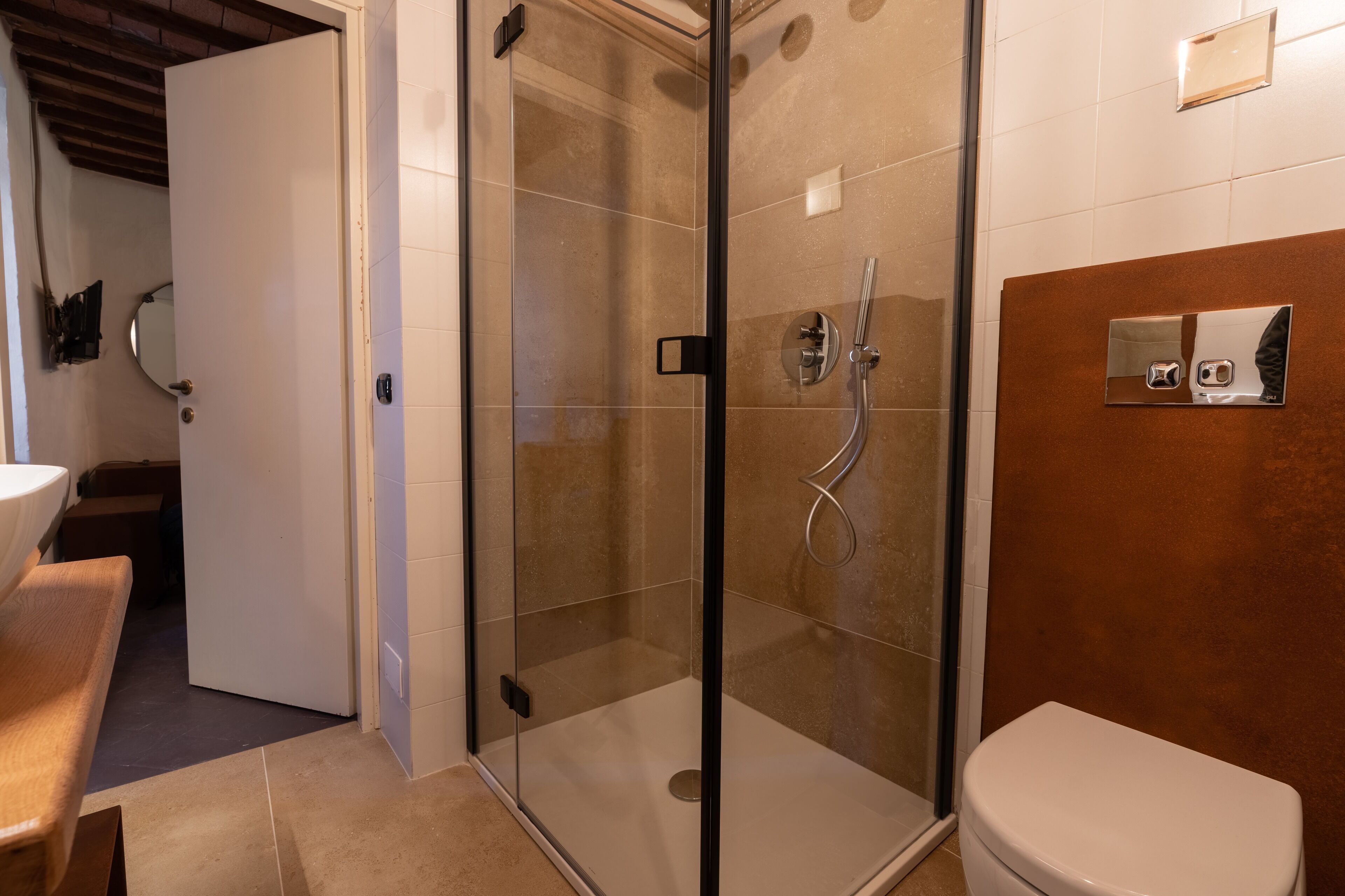 Un baño con ducha compartimentada con vidrio, inodoro y lavamanos.