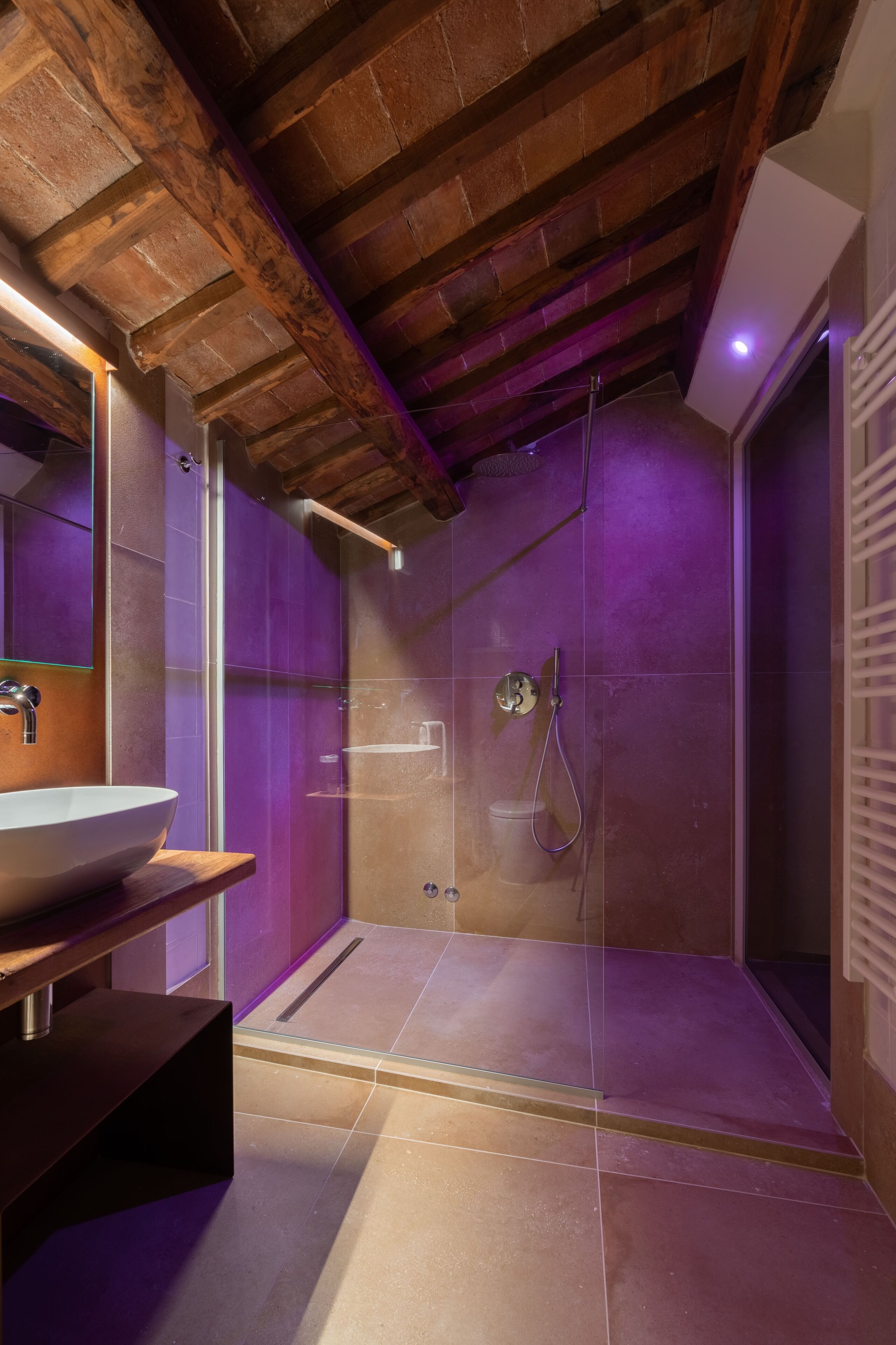 A modern bathroom with a glass-enclosed shower, a wooden ceiling, and a large mirror.