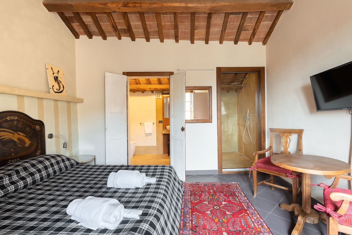 A hotel room with a bed, a chair, a table, and a TV.