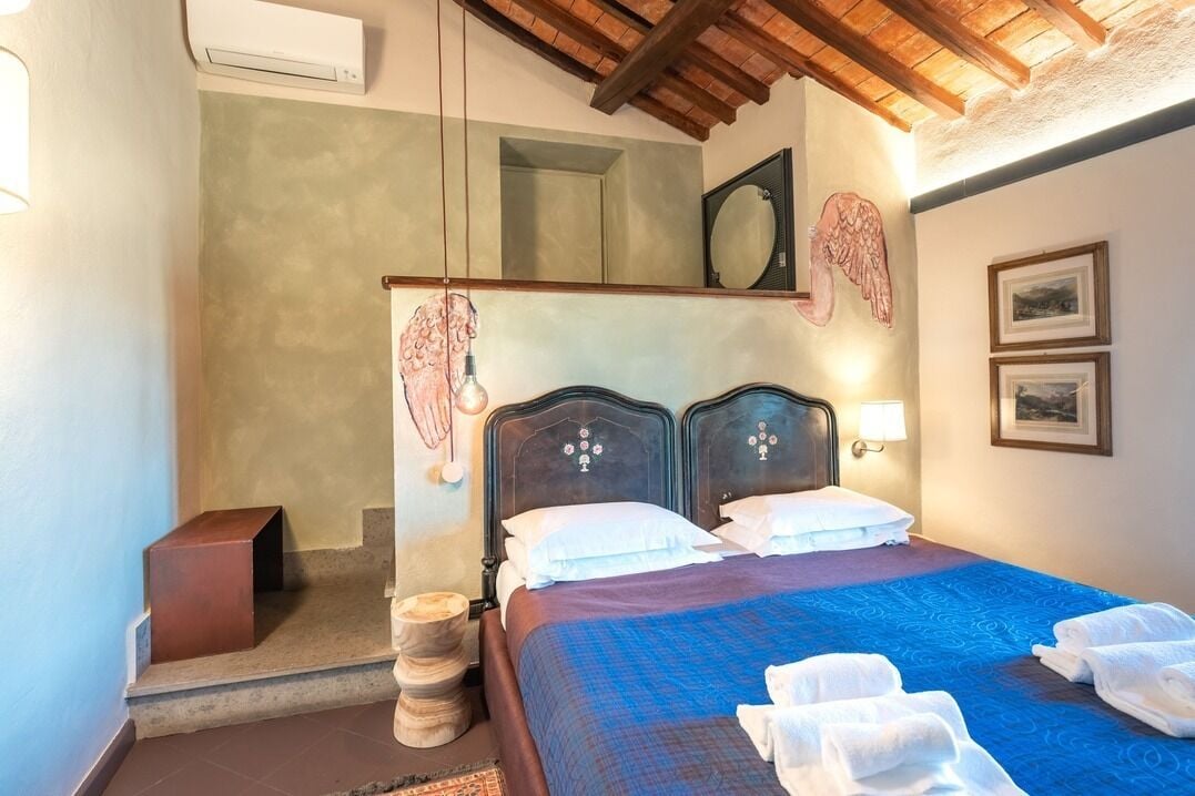 A bedroom with a bed, a wooden headboard, a nightstand, a mirror, and framed pictures on the wall.