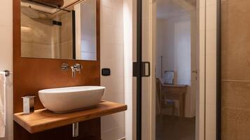 A modern bathroom with a large mirror, wooden vanity, and a glass shower enclosure.