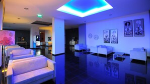 A modern lobby with white sofas, a reception desk, and artwork on the walls.
