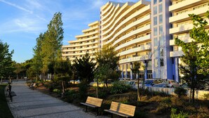 A modern building with multiple balconies and a paved walkway with benches.