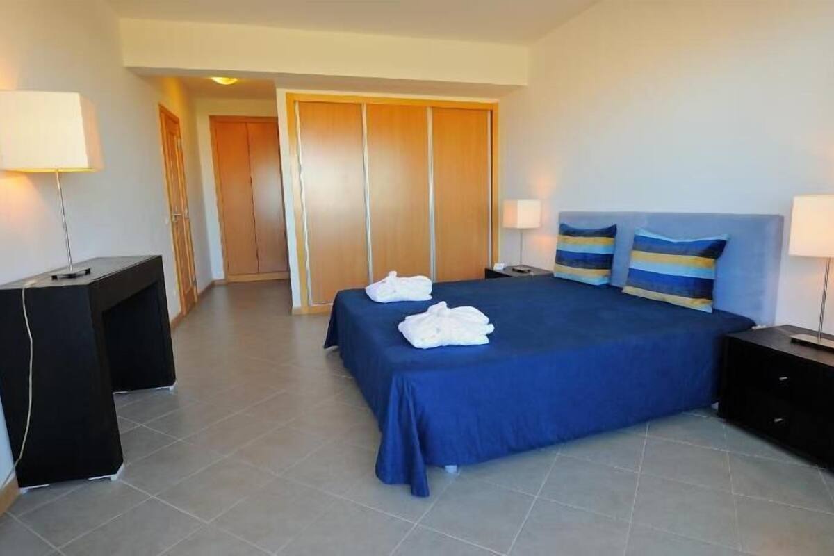 Una camera d'albergo con un letto, due lampade da comodino, una scrivania e un armadio.