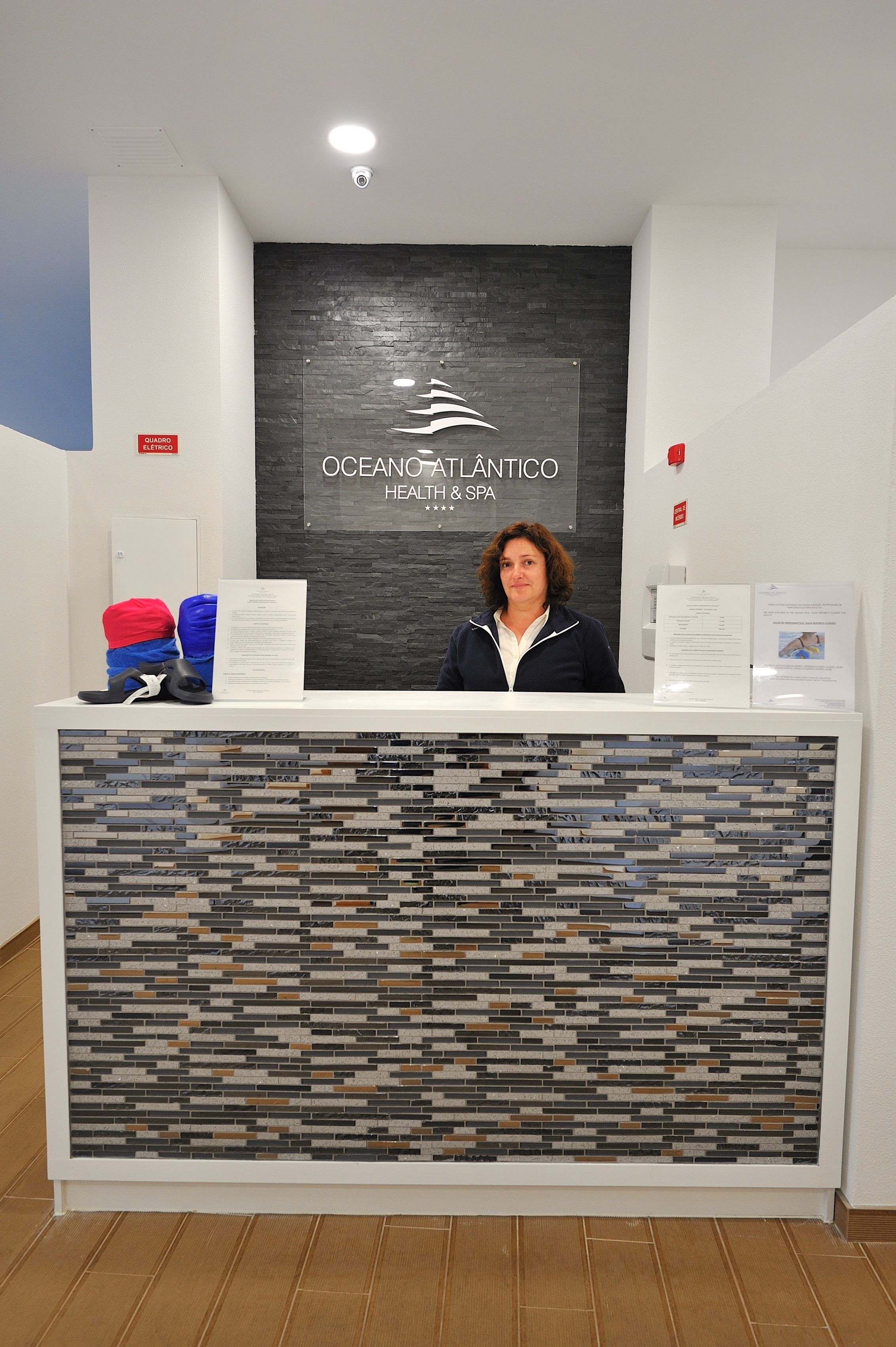 A reception desk with a logo for Ocean Atlantico Health & Spa, a white counter, and a patterned wall.
