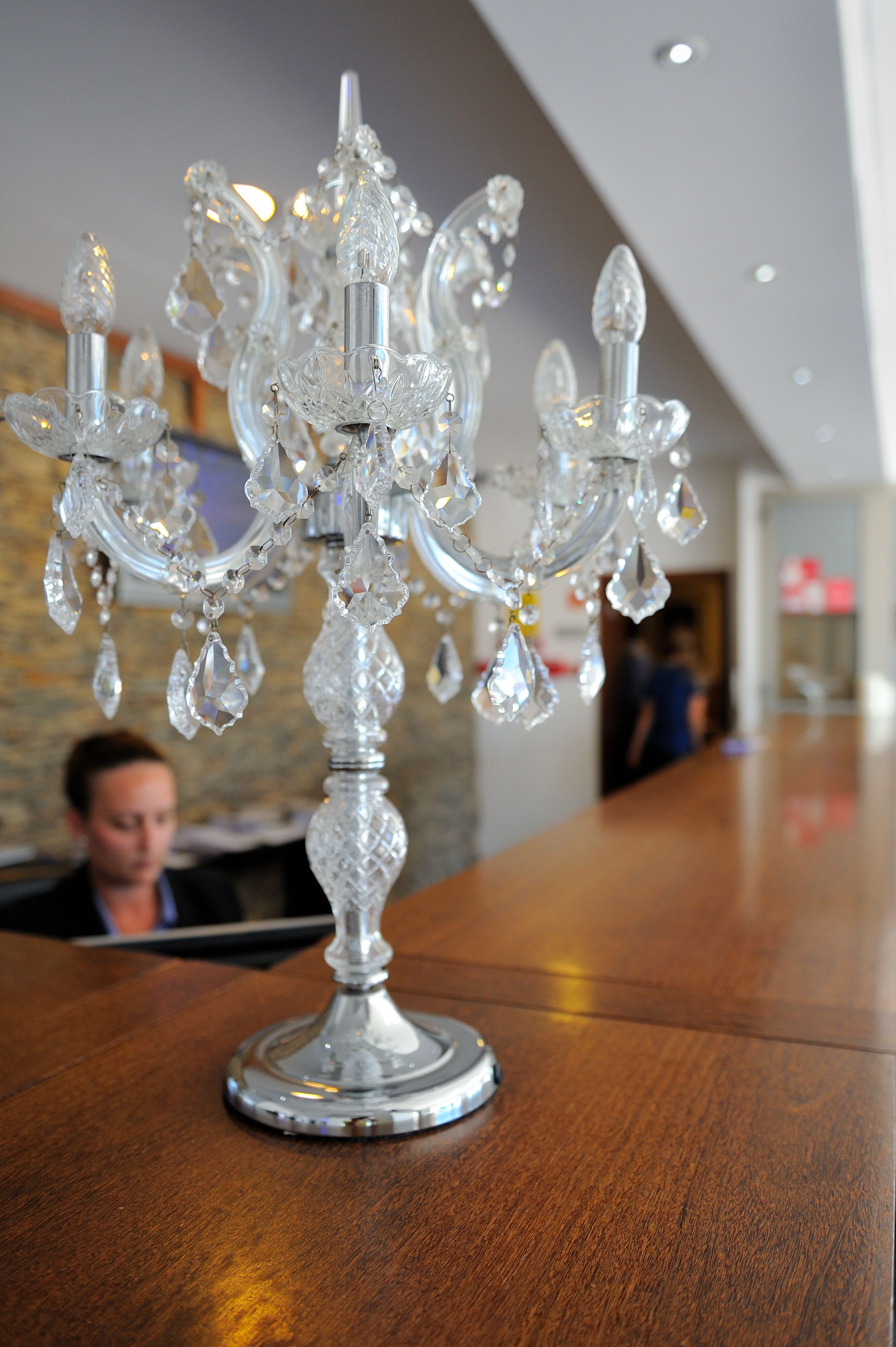 Um candelabro com vários braços e detalhes em cristal sobre uma mesa de madeira.